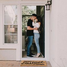 a man and woman kissing in front of a door with the words home sweet on it