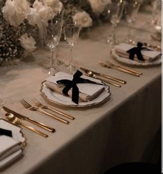 the table is set with gold and black place settings, silverware, and flowers