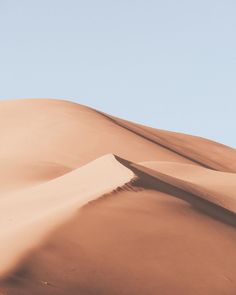 a person standing on top of a large sand dune in the middle of the desert