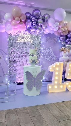 a birthday party with balloons and lights on the wall, including a cake in the shape of a butterfly