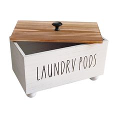 a wooden box with the word laundry pods printed on it and a black handle sits in front of a white background