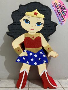 a paper cut out of a wonder woman sitting on top of a tile floor next to a wall