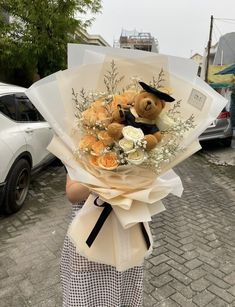 a woman holding a bouquet of flowers with a teddy bear in the center and an envelope behind her