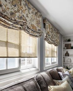 a living room filled with furniture and windows covered in roman blind shades on top of them