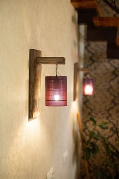 a red lamp hanging from the side of a wall next to a wooden frame and light fixture