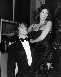 a man in a tuxedo is being lifted by a woman wearing a dress