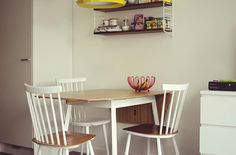 two white chairs sitting at a table in front of a flat screen tv on top of a wooden shelf