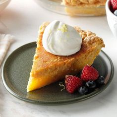 a piece of pie on a plate with berries and whipped cream