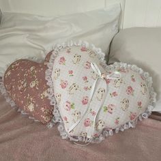 two heart shaped pillows sitting on top of a bed next to pillows with teddy bears