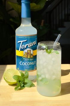 a bottle of torani next to a glass filled with ice and minty water