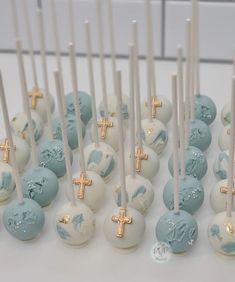 there are many blue and white cake pops with gold crosses on them