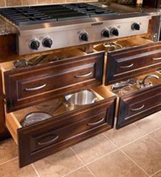 the drawers are open to show pots and pans on the stove top in this kitchen