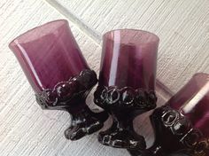 three purple glass candlesticks sitting on top of a white table next to each other