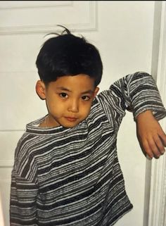 a young boy standing in front of a white door