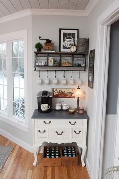 a kitchen with white cabinets and shelves filled with bottles on top of wooden flooring