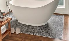 a white bath tub sitting on top of a wooden floor next to a shower stall