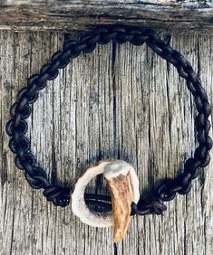 a piece of wood with a black chain around it and a white bead on the end