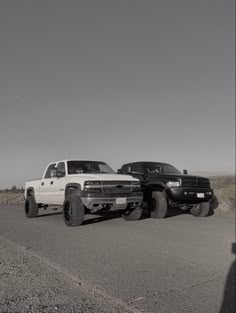 two pickup trucks are parked on the side of the road