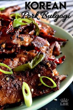 a plate filled with meat and vegetables on top of a striped table cloth next to chopsticks