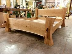 a wooden bed frame sitting on top of a floor in a room filled with furniture