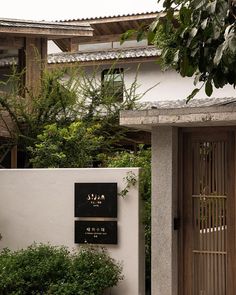 a white building with a black sign on it's side and trees in the background