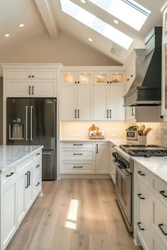 a large kitchen with white cabinets and stainless steel appliances, along with skylights in the ceiling