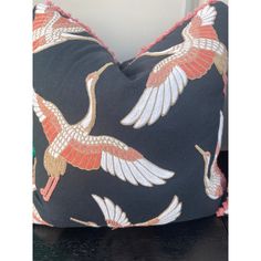 a black pillow with red and white cranes on it's side, sitting on a table