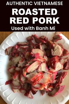 a white plate topped with sliced meat on top of a wooden table next to a bottle of red pork