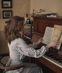 a woman sitting at a piano with an open book