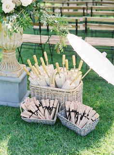 an arrangement of umbrellas and forks in baskets on the grass with flowers behind them