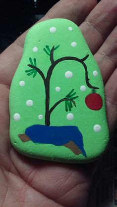 a hand holding a painted rock in the shape of a tree