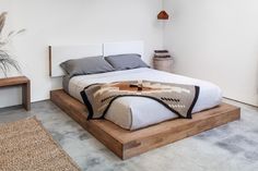 a bed sitting on top of a wooden platform next to a plant in a room