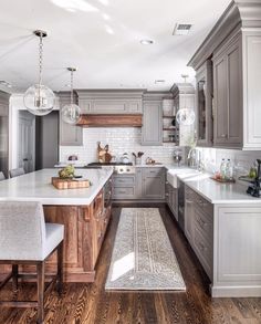 a large kitchen with gray cabinets and white counter tops, along with wooden flooring