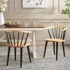 two wooden chairs sitting on top of a rug in front of a table with flowers