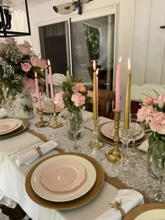 the table is set with pink flowers and gold place settings for dinner or brunch