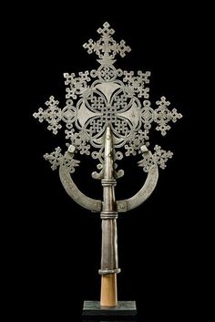 an intricately designed metal object on a wooden stand with a hammer in it's center