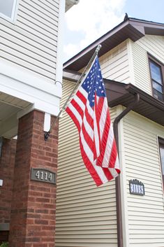 an american flag hanging from the side of a house