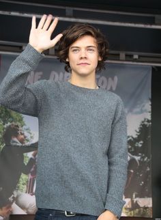 a young man waves while standing in front of a stage