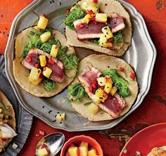 three tacos with meat, pineapples and other toppings on a plate