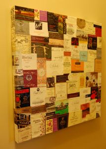 a wall covered in lots of different types of wine bottle labels and magnets on it