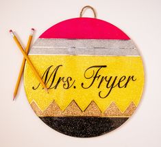 an ornament with the name mrs fryer on it and two pencils next to it