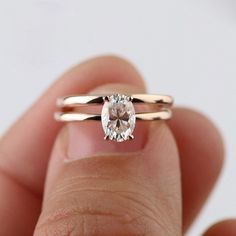 a close up of a person's hand holding a ring with a diamond in it