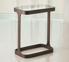 a glass and metal end table on the floor