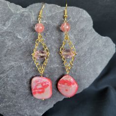 Add a playful pop of color to your accessory collection with our Pink Shell Trapeze Earrings! Made with a pink shell bead on a trapeze chain, these earrings also feature clear pink and round pink beads for a fun and unique look. Perfect for any occasion! Pink Chandelier Drop Earrings For Gift, Pink Beaded Crystal Earrings For Party, Handmade Pink Crystal Drop Earrings, Trendy Pink Beaded Earrings With Round Beads, Pink Jewelry For Gifts, Pierced Ears, Pink Chandelier Earrings For Summer Party, Pink Gold Dangle Earrings With Ear Wire, Trendy Pink Beaded Earrings, Elegant Pink Beaded Earrings For Gift