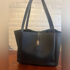 Dakota - Unknown Brand Black Vegan Leather Top Handle Bag. Gold Hardware. Snap Interior Closure. Vegan Leather Interior. Strap Top Closure W/Turn Lock. Three Exposed Interior Sections. Two Include Side Pockets. Great Condition - Unused. H - 10.5”, L- 12”, W- 5” Black Shoulder Bag With Snap Closure For Office, Workwear Tote Bag With Snap Closure, Black Bag With Magnetic Closure For Work, Black Shoulder Bag With Snap Closure For Work, Everyday Black Satchel With Snap Closure, Workwear Satchel Bag With Snap Closure, Workwear Shoulder Bag With Snap Closure, Black Workwear Shoulder Bag With Snap Closure, Snap Closure Satchel For Work