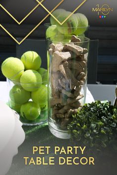 a glass filled with green tennis balls sitting on top of a table next to a pile of rocks