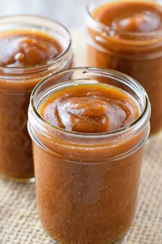 three jars filled with apple butter sitting on top of a table