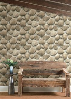 a wooden bench sitting in front of a wall with rocks on it's side