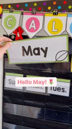 a person holding up a bulletin board with the word hello may in spanish on it