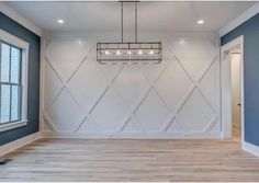 an empty room with white walls and wood flooring in the center is a chandelier